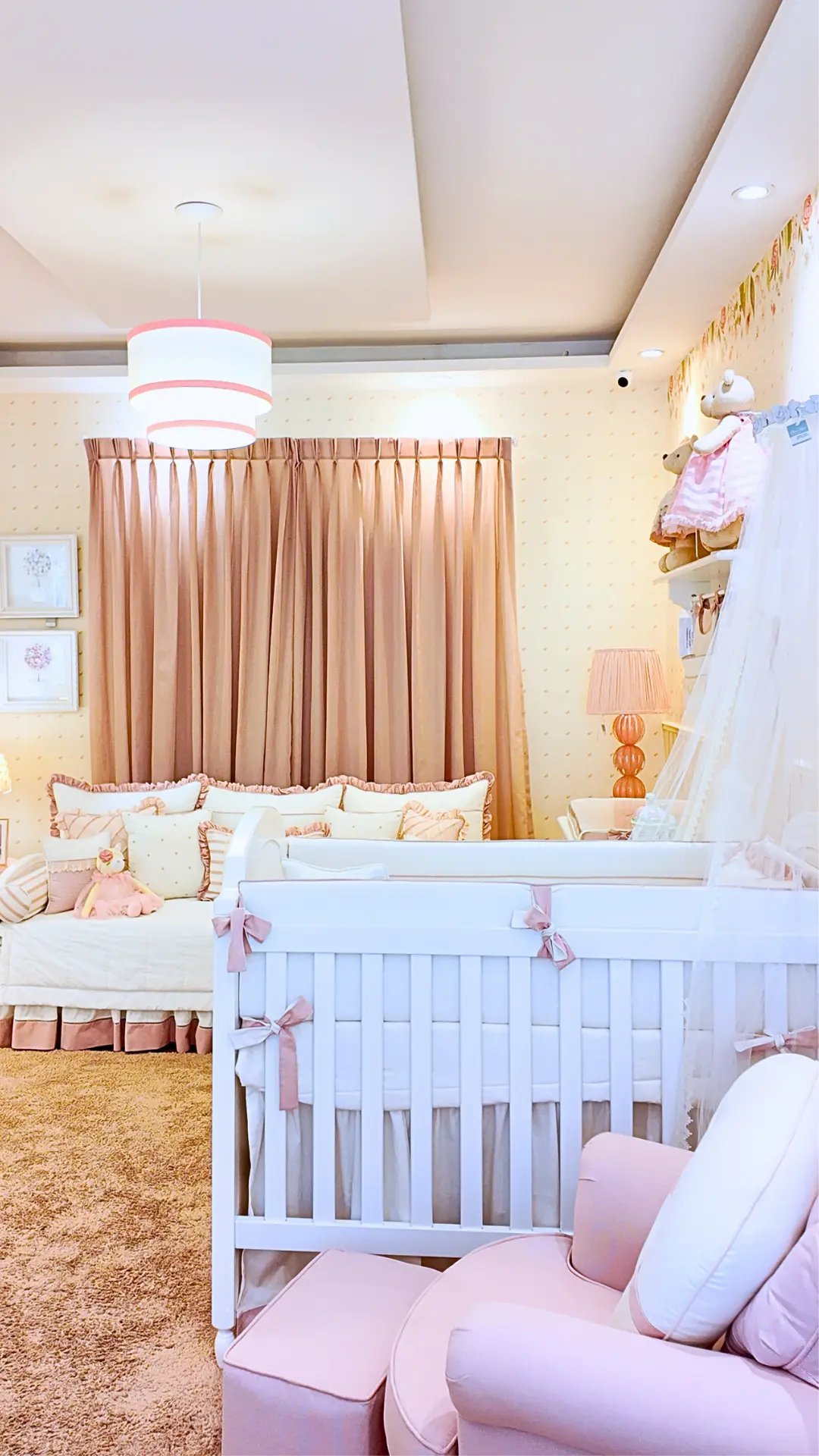 Quarto de bebê em tons rosa com berço branco e poltrona de amamentação